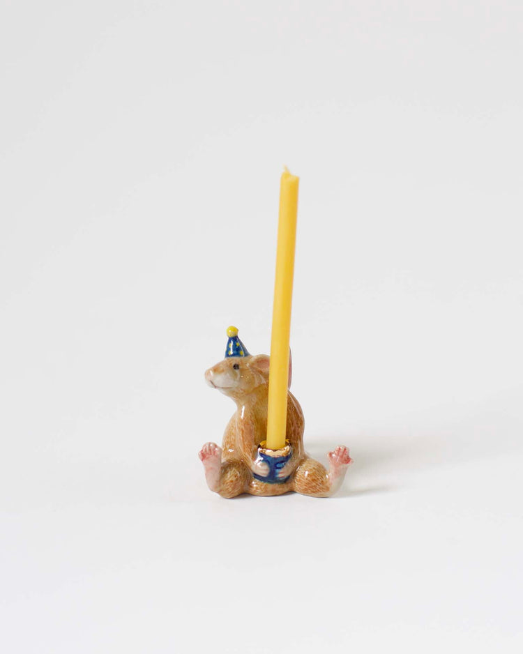 A small decorative hand-painted candle holder shaped like a squirrel, wearing a blue hat and holding a yellow candle, displayed against a white background.