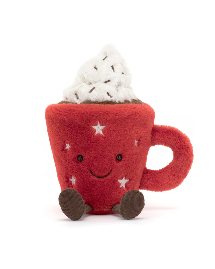 A Jellycat Amuseable Hot Chocolate, a plush toy in the shape of a comforting red mug with a handle and decorated with white stars. It has a smiling face and two small brown feet, topped with white fabric resembling whipped cream and sprinkles—a delightful companion to warm your heart.