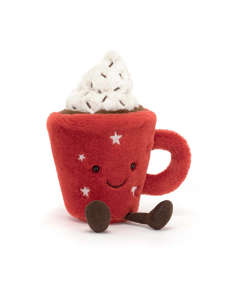 Amuseable Hot Chocolate by Jellycat is a plush toy shaped like a red mug with a handle, decorated with white stars, featuring a smiling face and topped with white whipped cream-like material. This comforting mug also has brown legs and feet.