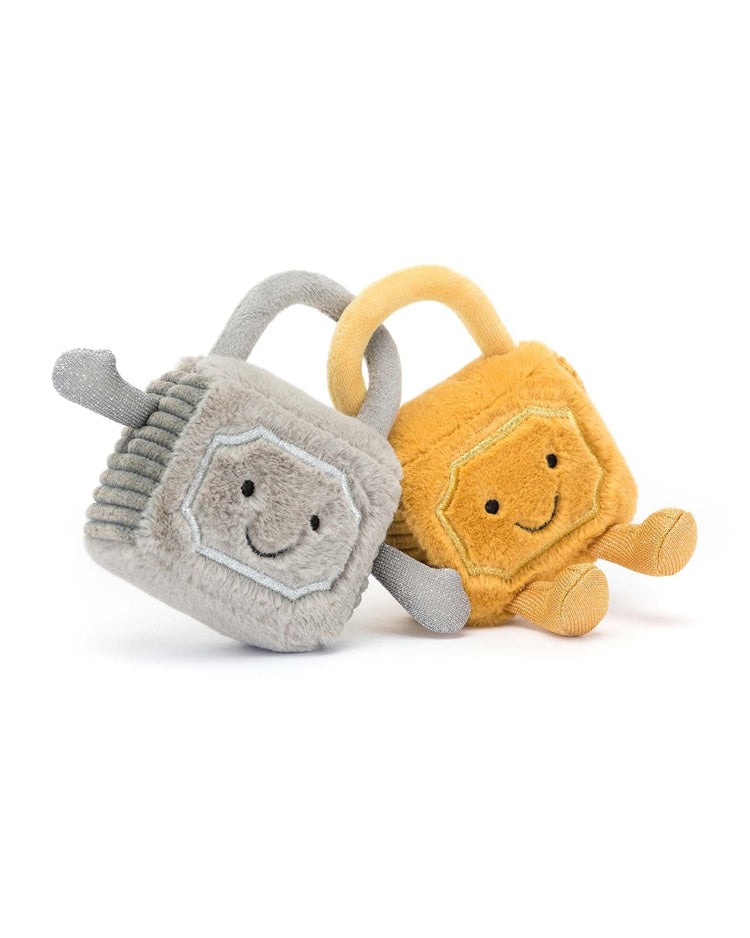 Two Amuseable Love Locks from Jellycat, one in gray and the other in yellow, both featuring embroidered smiling faces and arms, positioned against a white background. This adorable pair of stuffed animals is sure to brighten anyone’s day.