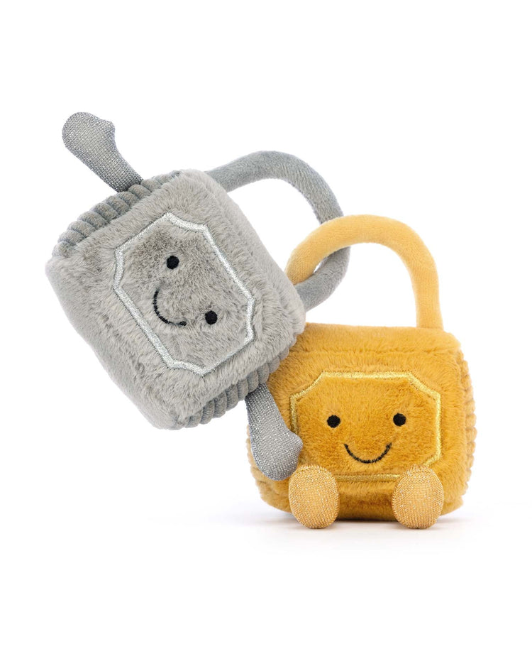 Two plush toys with smiling faces, Amuseable Love Locks by Jellycat are an adorable pair. One lock is grey with a flexible handle and the other is mustard yellow with a matching handle, both positioned closely together against a white background.