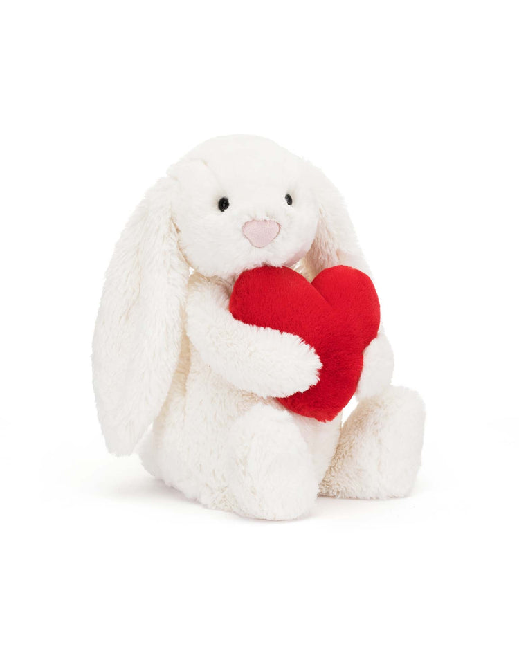 Introducing the Jellycat Bashful Red Love Heart Bunny Little: a plush white rabbit with long ears, cuddling a red heart-shaped pillow. With its super soft fur and endearing design, this adorable stuffed animal is the perfect cuddly companion.
