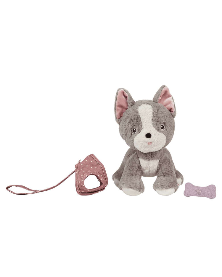 A gray and white dinkum dolls dinkum dog gizmo plush dog toy sits next to a pink polka dot leash and harness, with a small purple magnetic bone accessory nearby.