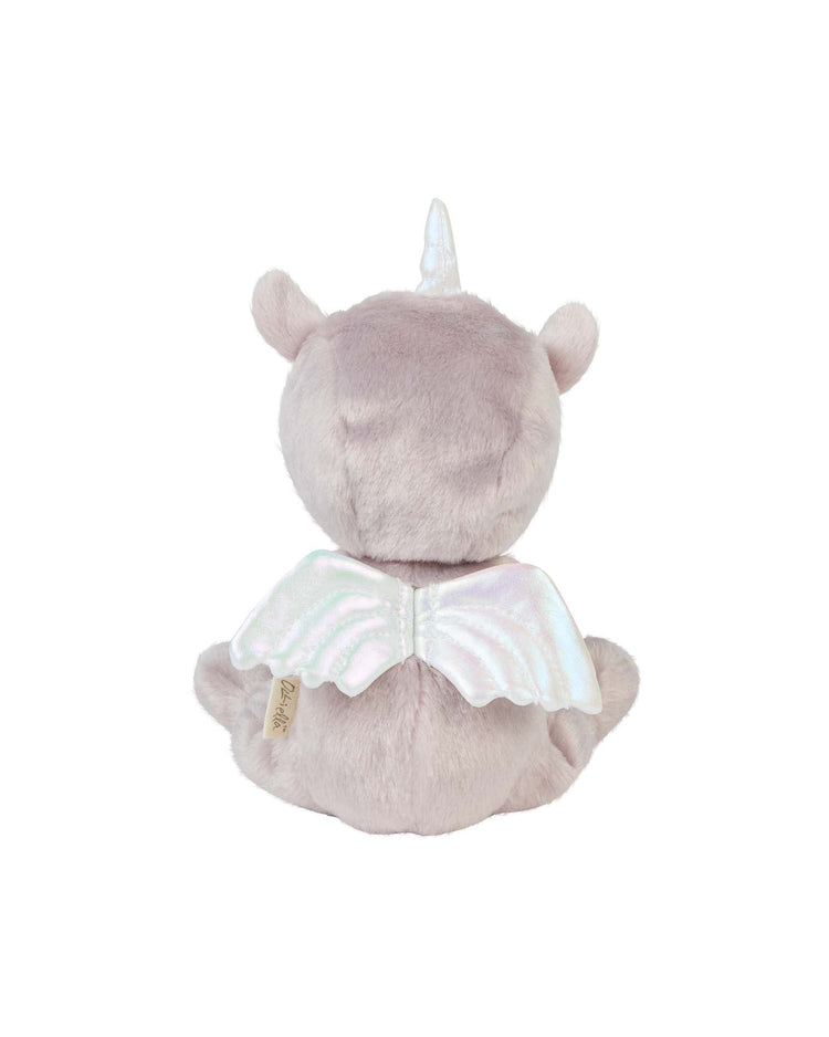 The dinky dinkum doll Uma Unicorn Lilac by Dinkum Dolls is shown from the back, seated with small ears, shimmery wings, a white horn, and a side fabric tag. This soft plush toy features a light purple color.