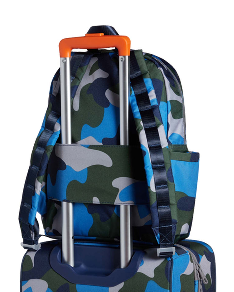 A Kane Kids Backpack in Navy Camo is fastened onto the handle of blue rolling luggage, complemented by State Bags' organizational zip pockets.