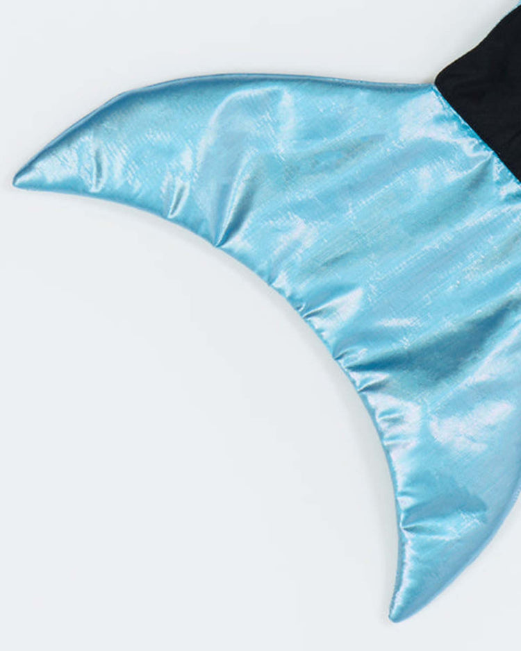 A sleek, light blue shark costume by meri meri with a subtle shimmer, lying flat against a plain white background—perfect for pairing with sea creature outfits or adding a magical touch to any ocean-themed dress up set.