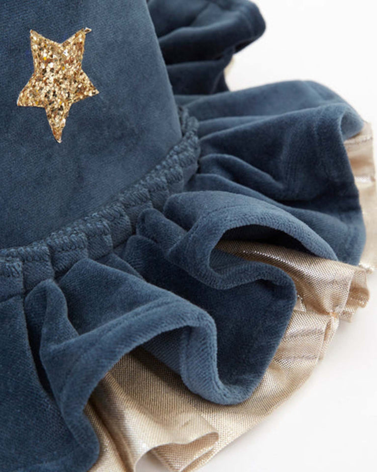 A close-up of the meri meri pointed blue hat, crafted from blue velvet fabric with gold ruffled trim and adorned with a gold glitter star decoration, reminiscent of a classic witch hat or an enchanting Halloween accessory.