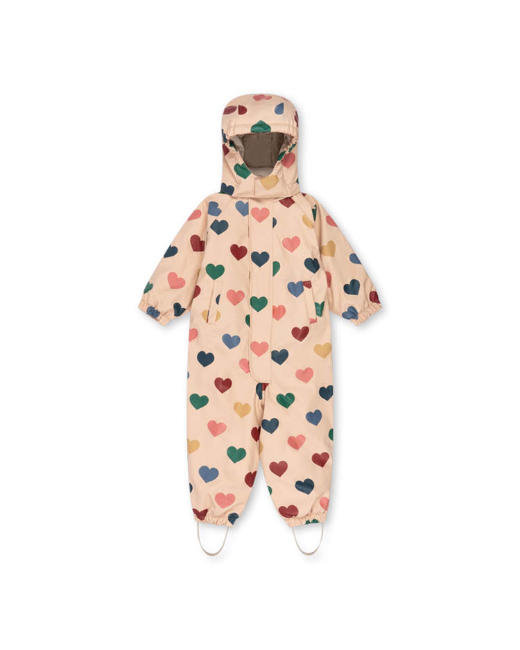 A "rain snowsuit in bon coeur coloré" by konges sløjd—a beige children's hooded jumpsuit featuring a multicolored heart pattern, elastic cuffs, and foot straps, fleece lined for extra warmth—is displayed flat on a white background.