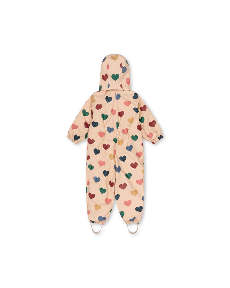 A "rain snowsuit in bon coeur coloré" by konges sløjd, featuring a beige children's hooded design with multicolored heart patterns, elastic cuffs and foot loops, and a cozy fleece lining for added warmth, displayed flat on a white background.