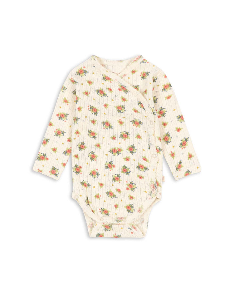 The minnie newborn bodysuit in rosetto by konges sløjd is an ivory long-sleeve baby bodysuit made from GOTS certified organic cotton, featuring a small floral print and convenient side snap buttons.