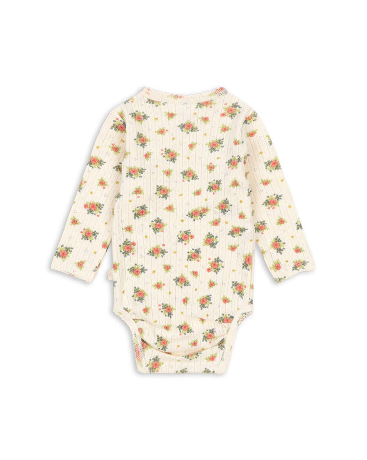 The minnie newborn bodysuit in rosetto by konges sløjd is a long-sleeved, cream-colored onesie with a ribbed texture, featuring a delicate floral print in shades of pink, yellow, and green. Crafted from soft organic cotton and GOTS certified for your peace of mind, the bodysuit is shown laid flat with the back side visible.