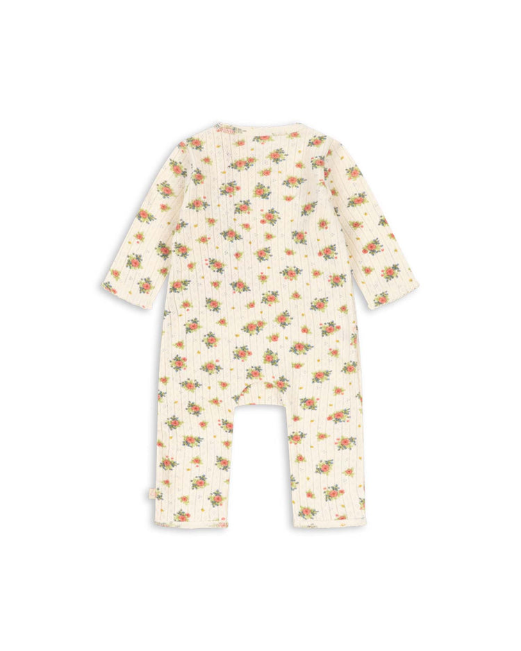 The minnie newborn onesie in rosetto by konges sløjd features long sleeves and legs, shown from the back. Made from soft, GOTS certified organic cotton with a ribbed texture, this cream-colored romper is adorned with a delicate floral print in red, yellow, and green tones—ensuring comfort and safety for your little one.