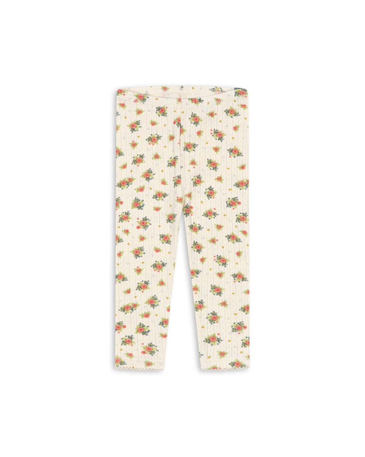 The "minnie pants in rosetto" by konges sløjd are cream-colored ribbed everyday leggings featuring a small red and green floral pattern throughout, crafted from organic cotton and shown laid flat against a white background.