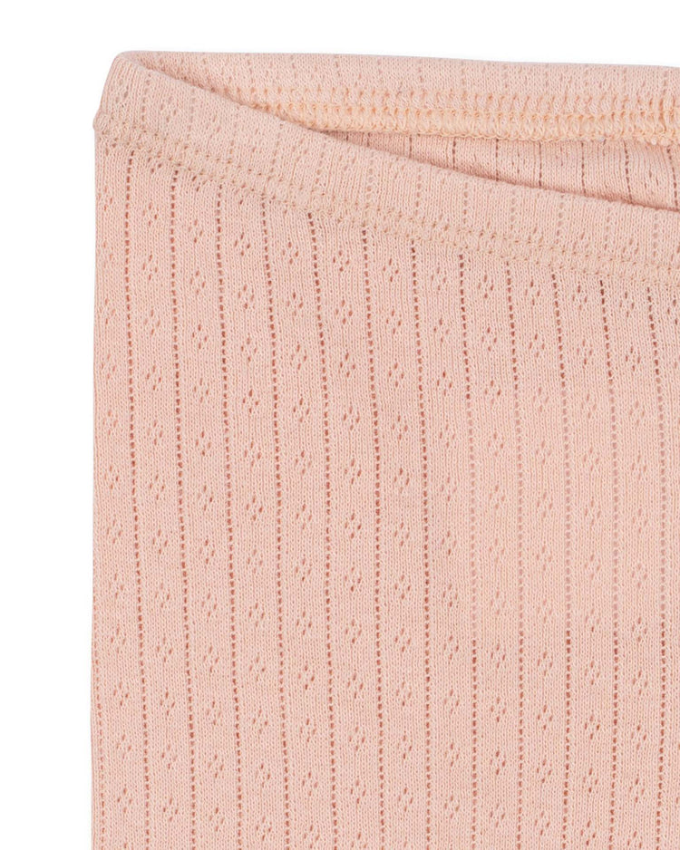 Close-up of the minnie pants in pale blush by konges sløjd, crafted from light pink ribbed knit fabric with delicate eyelet details—an ideal choice for soft basic essentials like organic cotton or pointelle leggings.
