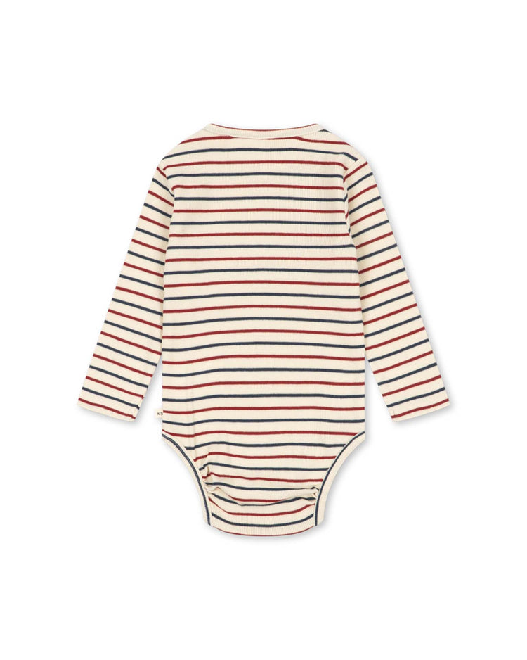 The voco modal bodysuit in tricolore bleu by konges sløjd is a long-sleeve baby bodysuit crafted from a soft modal blend, featuring horizontal stripes in red, black, and beige. Shown from the back, the gentle fabric rests comfortably against the skin, while convenient snap closures at the bottom ensure easy changes.