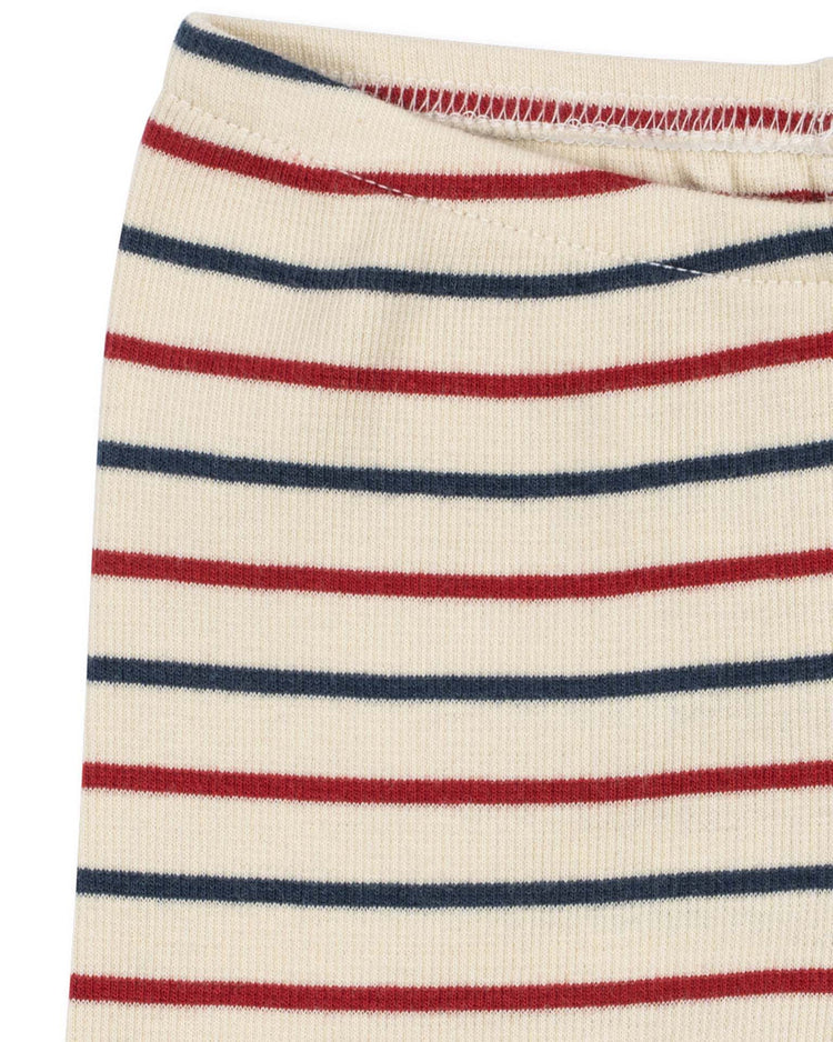 Close-up of the konges sløjd voco modal pants in tricolore bleu, featuring cream-colored ribbed fabric with horizontal red and navy blue stripes and a hint of the elastic waistband at the top. Crafted from a soft modal blend, these breathable pants provide both comfort and style.