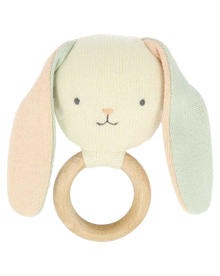 A knitted Meri Meri bunny baby rattle toy with a wooden ring that makes a gentle rattle sound.