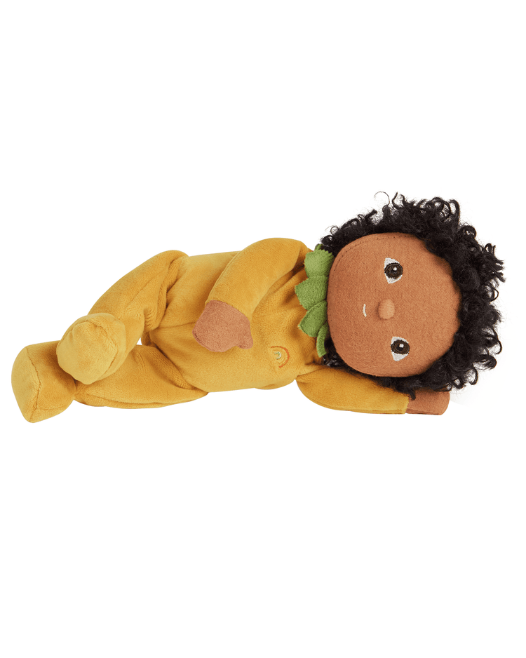 The Dinky Dinkums Pippa Pineapple by Dinkum Dolls is a limited-edition plush doll with curly black hair, brown skin, and large brown eyes, dressed in a yellow outfit with green ruffles and lying on its side.