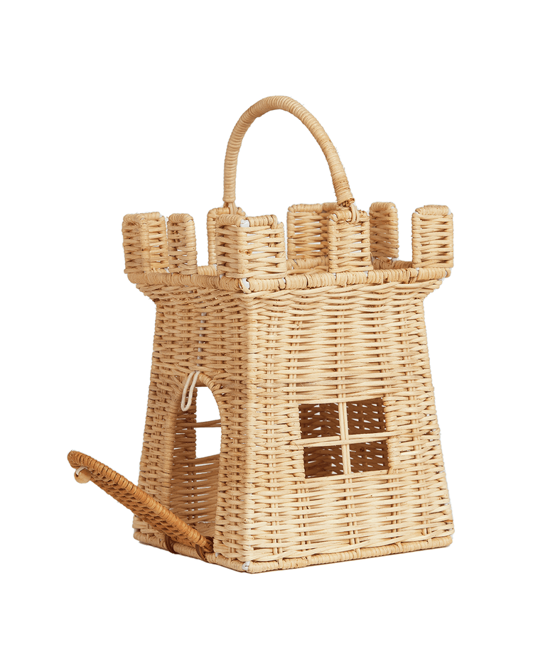 The dinkum dolls rattan castle bag is a charming, handwoven basket featuring turret details, a carry handle, a grid window, and a unique drawbridge-style door that opens downward.