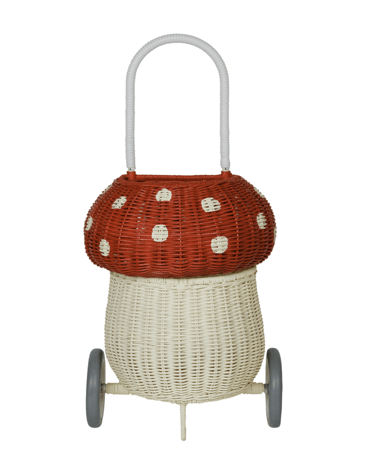 The dinkum dolls rattan mushroom luggy in red features a whimsical red-and-white mushroom design with gray wheels and a handle—perfect for playful toy storage and charming room decor.