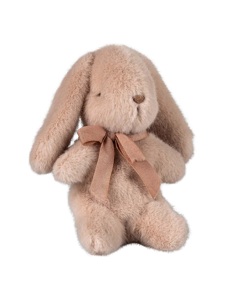 The Maileg mini bunny plush in light powder is a beige rabbit made from soft plush fabric, sitting upright with floppy ears and featuring a lovely light brown bow around its neck.