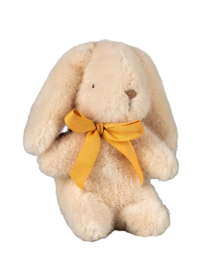 The mini bunny plush in cream by maileg is a delightful beige toy with long ears and a yellow bow, crafted from soft plush fabric, seated against a white background with a sweet appearance.