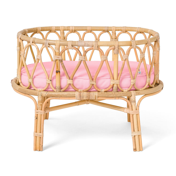 A small round rattan doll bed from the poppie toys Poppie Crib Classic Collection, featuring an open weave design, a pink cushion inside, and four short legs for support—perfect for displaying soft toys or adding a charming touch to any playroom. Inspired by the classic Poppie Crib style, this delightful piece blends function and whimsy.