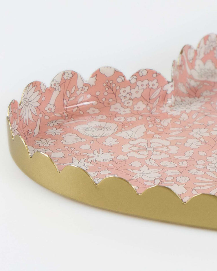 The meri meri x liberty heart small accessory tray is a heart-shaped jewelry holder with a pink Liberty floral print and scalloped gold edges, shown close up against a white background.