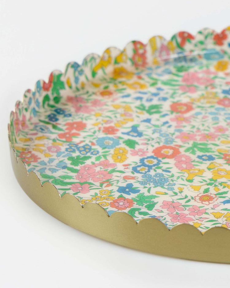 The meri meri x liberty round large accessory tray by meri meri features a scalloped edge, gold rim, and a vibrant Liberty floral pattern with colorful flowers on a white base—a charming accent for any space.
