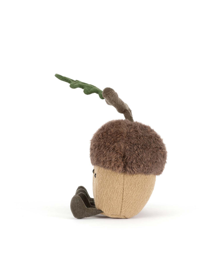 The Jellycat amuseables Ort & Tum Acorns plush toy, featuring a fuzzy brown cap, tan body, green stem, and two small legs, sits upright on a white background.