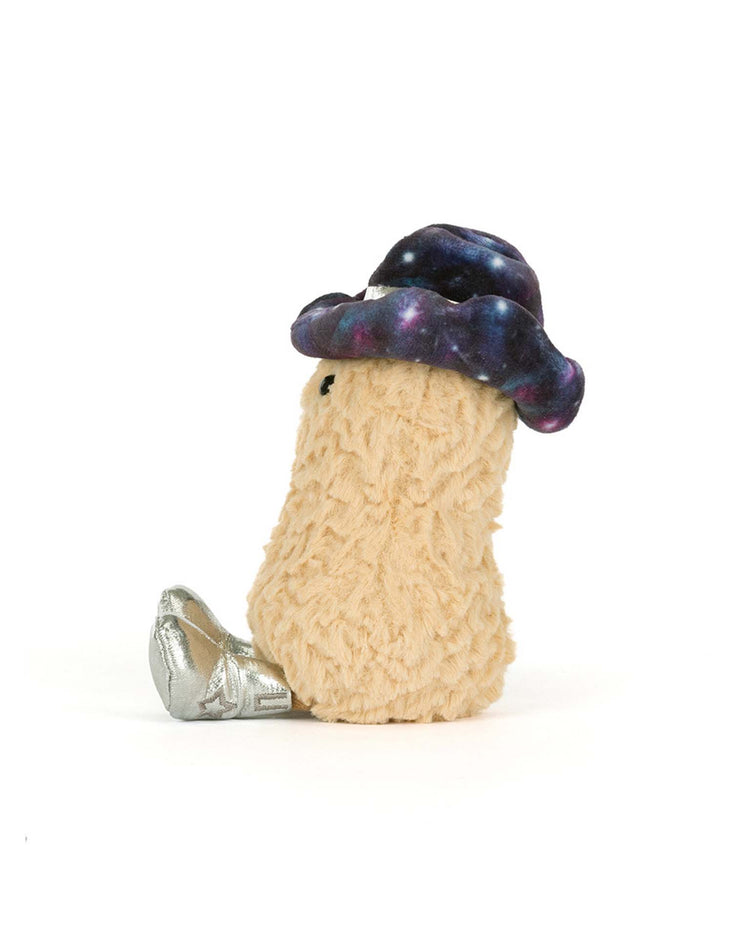 The jellycat amuseables peanut space rodeo outfit is a plush toy featuring a beige, fuzzy stem, a dark galaxy-patterned cap, and shiny silver shoes, sitting upright against a plain white background.