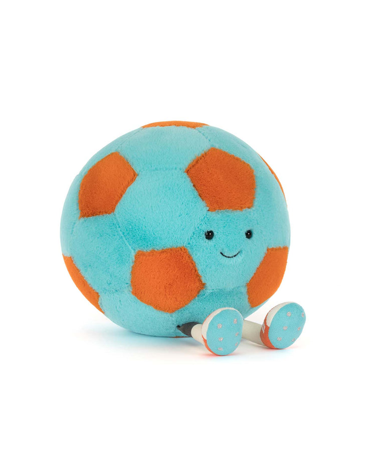 The amuseables jellycat soccer ball by Jellycat is a plush toy shaped like a soccer ball with blue and orange patches, a smiling face, and small white legs with blue polka dots, displayed on a white background.