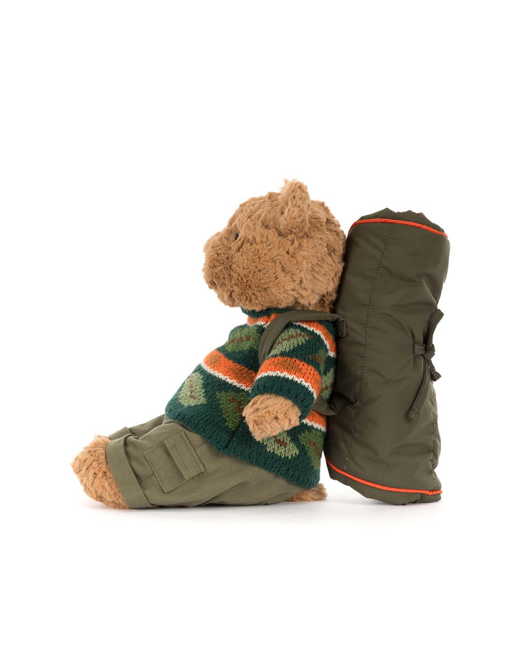 The Jellycat Bartholomew Bear Hiking Outfit features a charming plush bear dressed in a green patterned sweater, khaki pants, boots, and carrying a green sleeping bag—perfectly ready for camping or hiking adventures.
