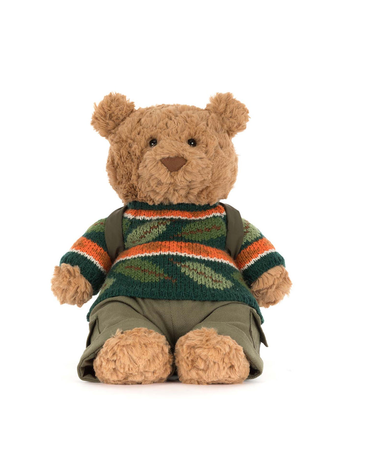 Bartholomew Bear by Jellycat sits upright against a plain white background, wearing the Hiking Outfit: green pants and a green, orange, and white striped sweater.