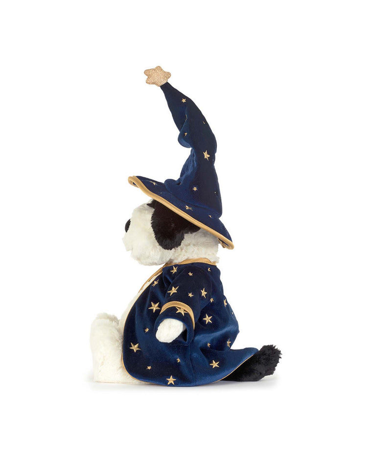 A Jellycat Rufferty Puppy plush toy wears a wizard outfit with a blue hat and robe decorated with gold stars, sitting upright and facing left against a white background.