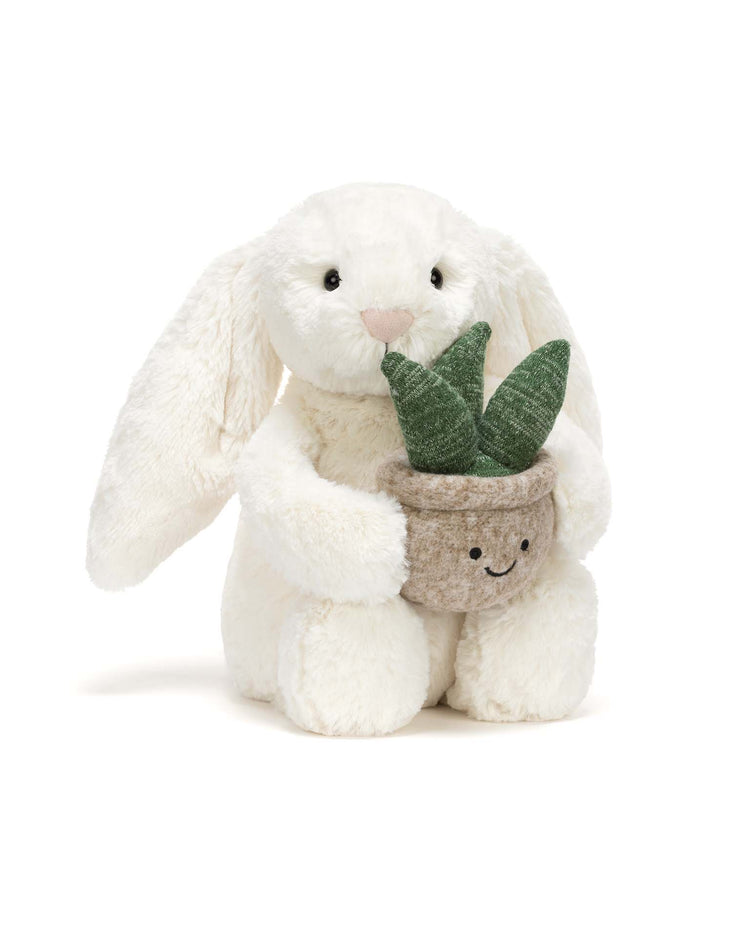 The Jellycat cream bunny with plant features a plush bunny with floppy ears holding a smiling potted plant. Both share warm expressions, making this adorable duo a perfect gift for any thoughtful occasion.