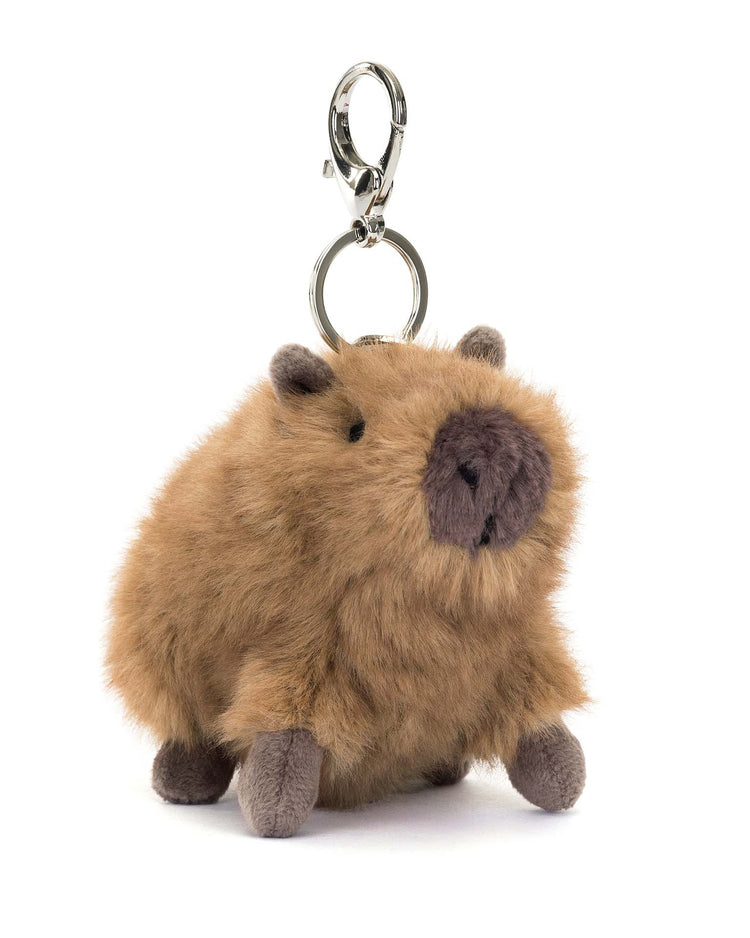 The Jellycat Clyde Capybara Bag Charm features brown fur and small ears, complete with a silver claw clip. This plush keychain sits on a white background, making it the perfect charming accessory for any bag.
