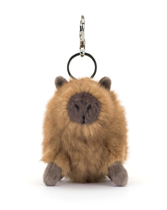 This plush keychain by Jellycat, called the Clyde Capybara Bag Charm, features fluffy brown fur and small ears. It has a sturdy metal key ring and a silver claw clip for easy attachment to your accessories, making it perfect as a bag charm.