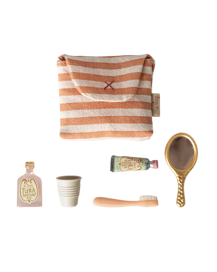 The maileg toothbrush set in bag, mouse - coral stripe, includes a small striped pouch with snap closure and miniature accessories—a bottle, cup, tube, hairbrush, and gold hand mirror—displayed on a white background.