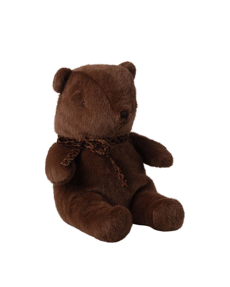 The maileg medium teddy bear plush in dark chocolate sits upright against a white background, featuring a leopard print ribbon around its neck. This soft, vintage-inspired bear is huggable and perfect for any collection.