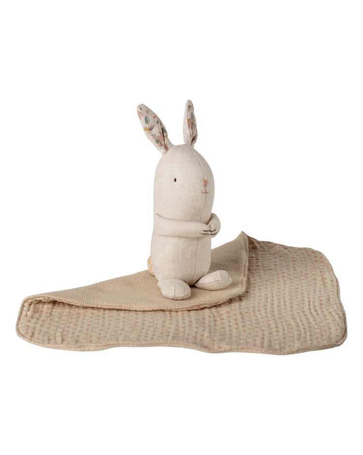 The maileg lullaby friends, bunny, mini - nature sits upright with floral inner ears beside a textured light brown cuddle cloth dotted with color, both on a white background—an adorable baby gift.