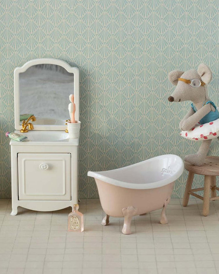 The "bathtub, mouse - rose" by Maileg features a plush mouse in a tutu sitting by a mini bathtub with vintage-style accessories and charming dollhouse furniture against patterned wallpaper.