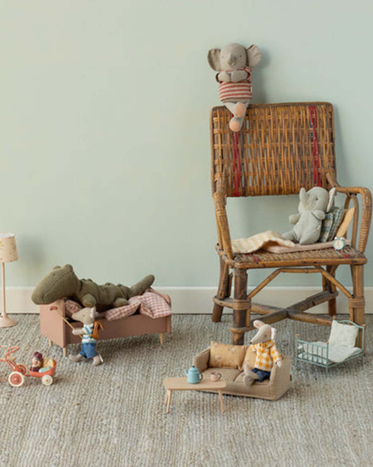 A cozy children's play scene showcases the maileg small crocodile in olive green from Safari Friends, arranged with soft toys on tiny furniture and accessories atop a textured carpet against a pale green wall.