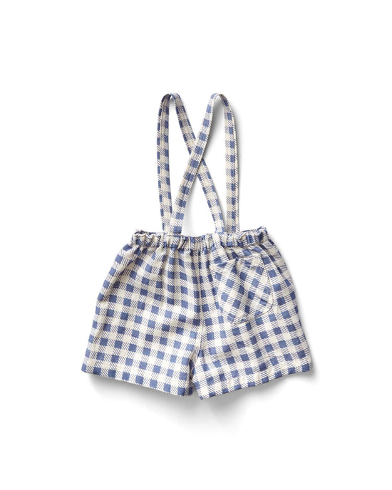 The enid shortall in gingham print, blueberry by soor ploom features charming blue and white checks with crossed suspenders. Made from soft cotton, these children's shorts rest elegantly against a crisp white background.