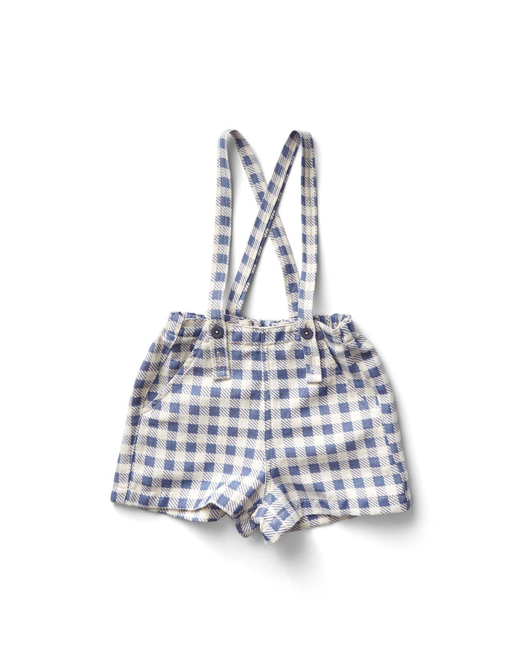 The Enid Shortall in blueberry gingham print by Soor Ploom features a pristine white background with suspenders.