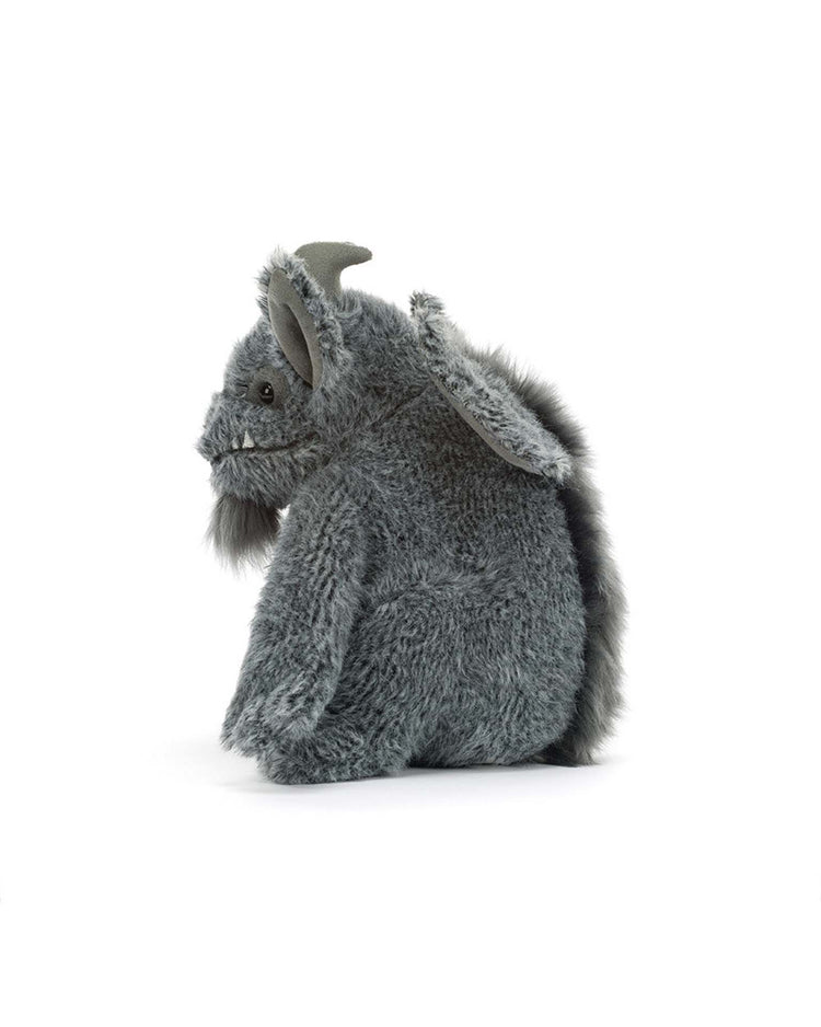 A Jellycat Growlston Gargoyle plush toy, featuring gray fur, pointy ears, small horns, a beard, and a fluffy tail, sits sideways against a white background.
