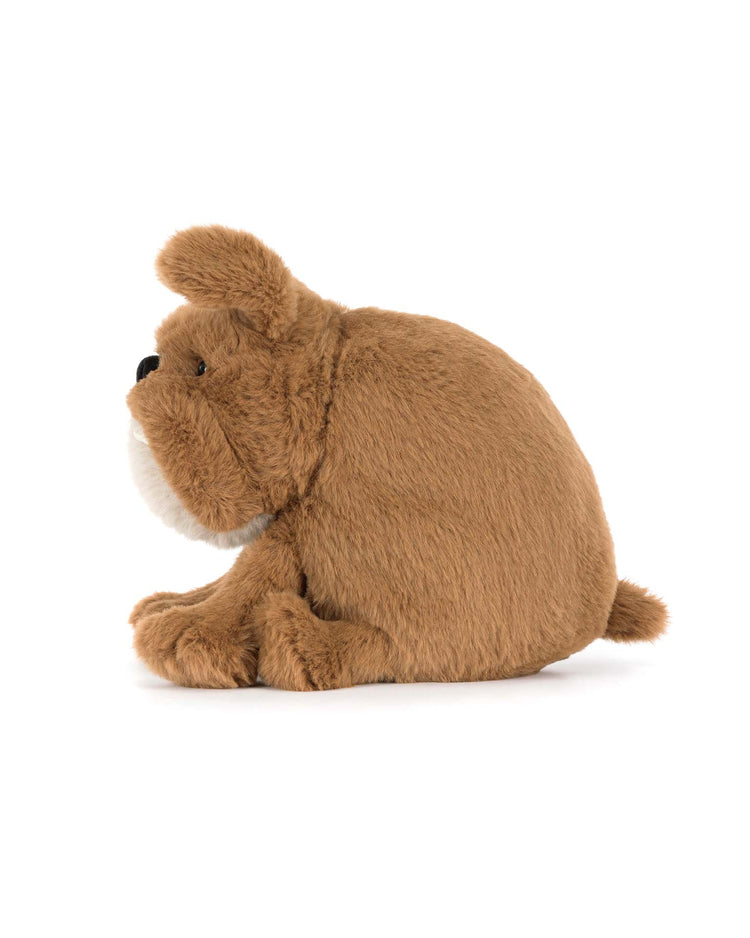 A brown plush stuffed animal, the Derreck Dog by Jellycat, shaped like a friendly bulldog, sits on a white background viewed from the side.