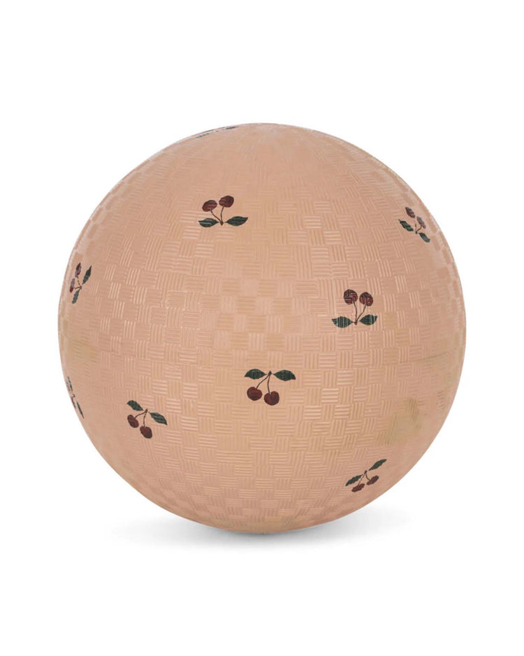 The "kids ball in cherry blush" by konges sløjd is a textured, light brown rubber ball featuring charming red cherry illustrations—ideal for outdoor play and active fun.