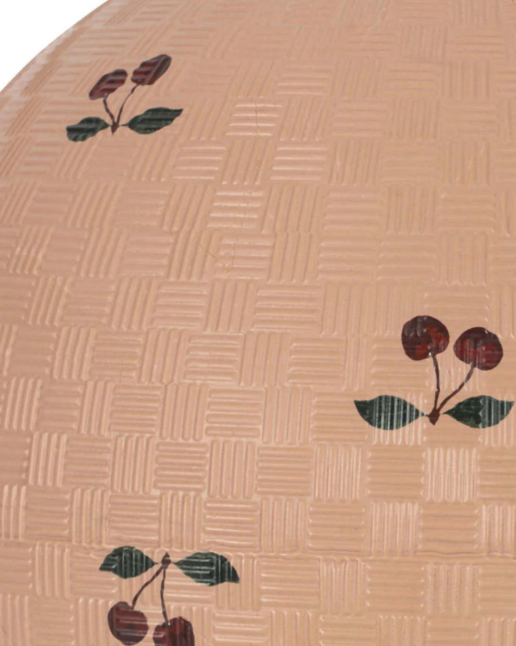 The konges sløjd kids ball in cherry blush features a tan, basket-weave texture decorated with painted cherry clusters and green leaves, evoking a playful outdoor toy for active games.