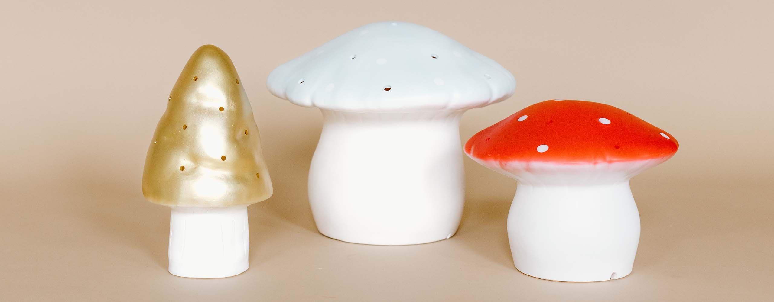 Three decorative ceramic mushrooms on a beige background.